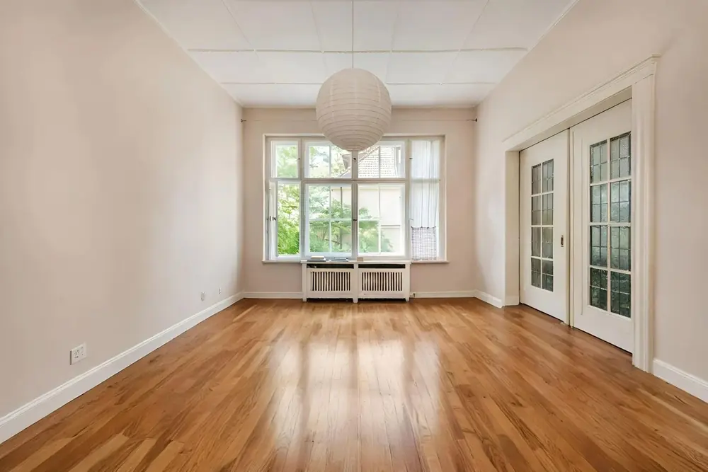 An empty room with french doors, then staged as a contemporary sitting room.